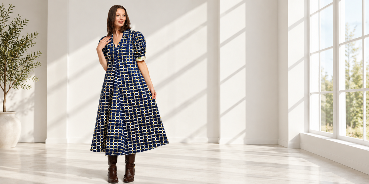 Model wearing a navy windowpane-check dress with puff sleeves in a bright white room